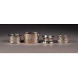 FOUR VARIOUS GEORGE V SILVER NAPKIN RINGS, including a HEAVY PLAIN, OVAL example, another pierced,