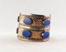 FOREIGN SILVER COLOURED METAL DOUBLE WIDTH BROAD OPEN BANGLE, the top set with six lapis lazuli oval