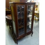 A CARVED MAHOGANY DWARF DISPLAY CABINET ENCLOSED BY TWO GLAZED DOORS, WITH CARVED APRON AND CABRIOLE