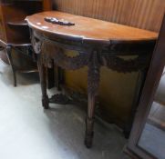 A CARVED MAHOGANY DEMI-LUNE SIDE TABLE, WITH FLORAL CARVED AND PIERCED FESTOON APRON, ON FOUR LEGS