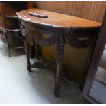 A CARVED MAHOGANY DEMI-LUNE SIDE TABLE, WITH FLORAL CARVED AND PIERCED FESTOON APRON, ON FOUR LEGS