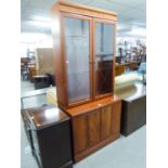 A MAHOGANY DISPLAY CABINET WITH TWO GLAZED DOORS ENCLOSING TWO PLATE GLASS SHELVES, ON AN ADVANCED