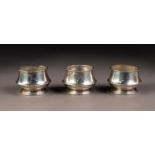 GEORGE VI SET OF THREE PLAIN SILVER OPEN SALTS, of circular, footed form, two with clear glass
