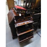 A WOODEN WALL RACK OF THREE TIERS WITH TWO SMALL DRAWERS IN THE BASE AND AN OBLONG TABOURET