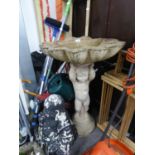 AN AGGREGATED STONE BIRDBATH WITH PUTTO COLUMN AND A LARGE SEATED DEITY GARDEN ORNAMENT (AS FOUND)