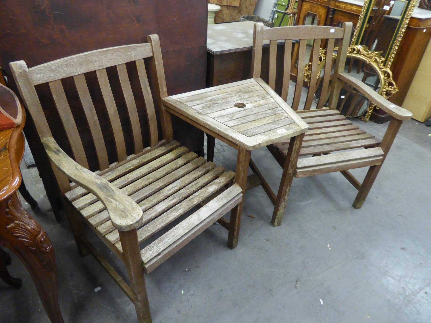 A TEAK COMBINED GARDEN TABLE, FLANKED BY TWO ARMCHAIRS (ANGLED)