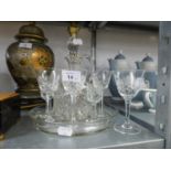 A CUT GLASS WINE JUG SET OF FOUR CUT GLASS SMALL STEM WINES OR LIQUEURS ON A CUT GLASS CIRCULAR TRAY