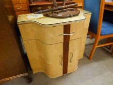 1960?S SMALL SIDE CABINET WITH SERPENTINE FRONT, FRIEZE DRAWER OVER A CUPBOARD WITH TWO DOORS AND