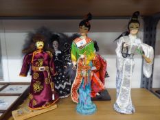 FOUR ELABORATELY DRESSED ORIENTAL FEMALE COSTUME DOLLS AND ANOTHER OF A MONGOLIAN WARRIOR, ALL