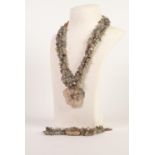 T.G.G.C. SOUTH CHINA TRIPLE STRAND NECKLACE OF CHIP GREEN JADE BEADS, with mother of pearl flower