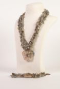 T.G.G.C. SOUTH CHINA TRIPLE STRAND NECKLACE OF CHIP GREEN JADE BEADS, with mother of pearl flower