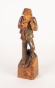 EUROPEAN CARVED SOFTWOOD FIGURE OF A WOODSMAN carrying his axe over his shoulder and smoking a pipe,