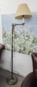 A BRASS FLOOR LAMP WITH SWINGING ARM TOP AND FABRIC SHADE