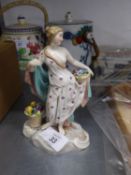 AN EARLY TWENTIETH CENTURY CONTINENTAL CERAMIC FIGURE OF A SEMI-DRAPED FEMALE FIGURE HOLDING A