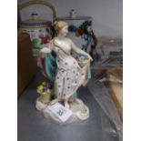 AN EARLY TWENTIETH CENTURY CONTINENTAL CERAMIC FIGURE OF A SEMI-DRAPED FEMALE FIGURE HOLDING A