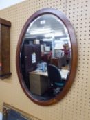AN OVAL BEVELLED EDGE WALL MIRROR, IN MAHOGANY FRAME