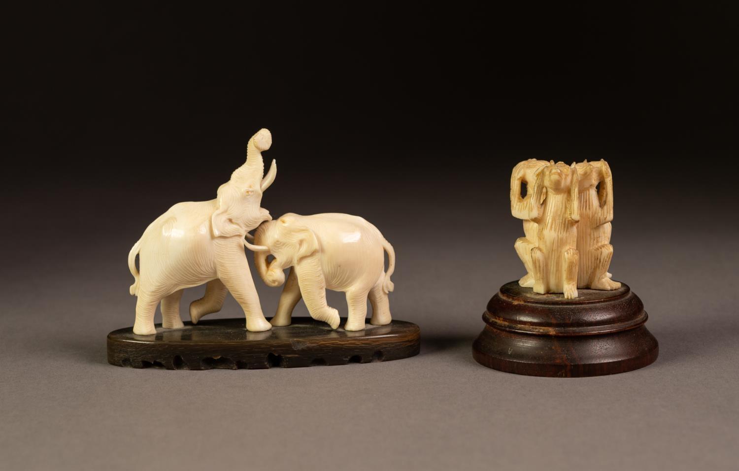 A SMALL CARVED IVORY MODEL OF TWO ELEPHANTS FIGHTING, on an elliptical horn base, 3 3/4" (9.5cm)