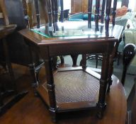 A MAHOGANY OCTAGONAL COFFEE TABLE WITH BEVELLED GLASS TOP AND CANE UNDERPLATFORM