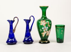 TWO SMALL SAPPHIRE BLUE GLASS ENAMELLED AND GILT DECORATED EWERS, a green tinted enamelled and