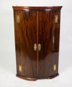 GEORGE III MAHOGANY BOW FRONTED CORNER CUPBOARD, of typical form with exposed brass H hinges,