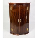 GEORGE III MAHOGANY BOW FRONTED CORNER CUPBOARD, of typical form with exposed brass H hinges,