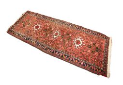 EASTERN RUNNER with a row of seven alternating medallions, on a wine red field with scattered