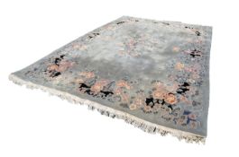 LARGE WASHED CHINESE CARPET, with a plain pale blue/grey field, embossed oval floral centre
