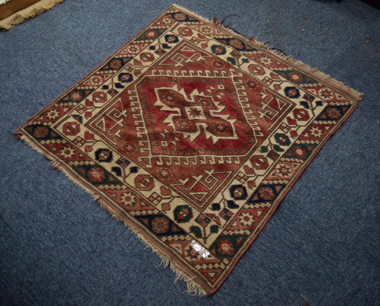 SMALL EASTERN RUG, the red field filled with a centre medallion within a diamond shaped latch hook