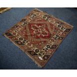 SMALL EASTERN RUG, the red field filled with a centre medallion within a diamond shaped latch hook