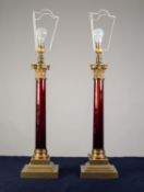 LARGE PAIR OF BRASS AND RED GLASS TABLE LAMPS, each of Corinthian column form with square, stepped
