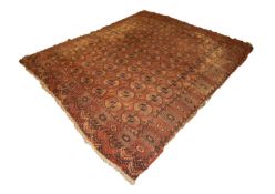 OLD TURKOMAN BOKHARA CARPET with seven rows of twelve octagonal guls on a wine red field, broad