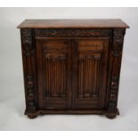 AGED OAK SIDE CABINET, the plain top above a cupboard enclosed with a pair of carved linen-old