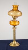 BRASS CORINTHIAN COLUMN PATTERN OIL TABLE LAMP, with circular, stepped base, moulded amber glass