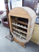 A PINE OVAL FRAMED 21 BOTTLE WINE RACK OF FOUR TIERS WITH A TOP TIER FOR WINE GLASSES, ON TRESTLE