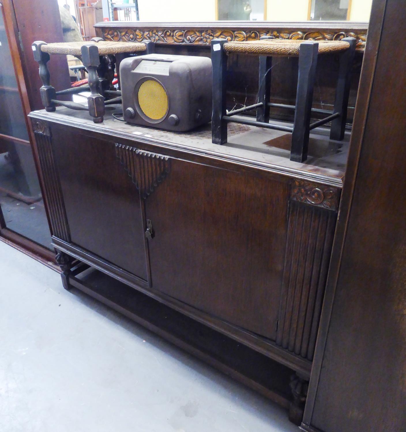 A 1930's GOOD QUALITY OAK SIDEBOARD WITH LOW CARVED BACK, HAVING TWO SOLID DOORS, INTERIOR WITH