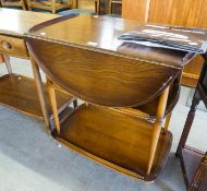 AN ELM THREE TIER PEMBROKE TEA TROLLEY WITH CIRCULAR FALL-LEAF TOP, ON SHEPHERD?S CASTORS (ERCOL)