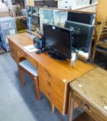 A TEAK LONG, LOW KNEEHOLE DRESSING TABLE WITH SEVEN DRAWERS AND FULL-WIDTH MIRROR AND THE DRESSING