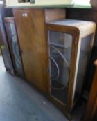 AN ART DECO CHINA DISPLAY CABINET WITH STEPPED TOP, HAVING CENTRAL PANEL DOOR, FLANKED BY TWO GLAZED