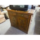 A SMALL MAHOGANY CARVED SIDEBOARD/CUPBOARD WITH TWO DRAWERS OVER TWO CUPBOARDS (SPLITS TO TOP)