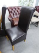 A SET OF FOUR DINING CHAIRS, WITH UPHOLSTERED HIGH BACKS AND SEAT COVERED IN BLACK HIDE