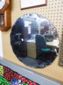 A CIRCULAR FRAMELESS WALL MIRROR WITH FANCY BEVELLED EDGE