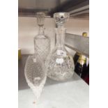 A CUT GLASS SQUARE DECANTER AND STOPPER, A CUT GLASS DOMED SHAPED DECANTER AND STOPPER AND A GLASS
