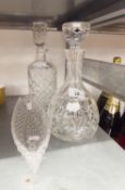 A CUT GLASS SQUARE DECANTER AND STOPPER, A CUT GLASS DOMED SHAPED DECANTER AND STOPPER AND A GLASS