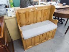 A SMALL PINE MONKS BENCH WITH FOUR SMALL PANEL BACK, LIFT UP SEAT AND A SEAT CUSHION