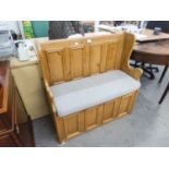 A SMALL PINE MONKS BENCH WITH FOUR SMALL PANEL BACK, LIFT UP SEAT AND A SEAT CUSHION