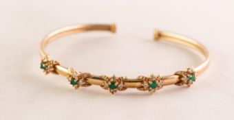 9ct GOLD NARROW TORQUE BANGLE, the top set with five clusters each with a small centre emerald and