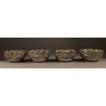 SET OF FOUR ORIENTAL EMBOSSED SILVER COLOURED METAL BOWLS, each of scalloped form, decorated with