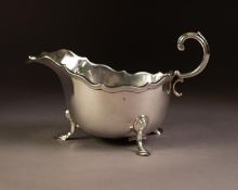 GEORGIAN STYLE SILVER SAUCE BOAT, oval with moulded wavy edge, free scroll handle, raised on three