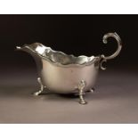 GEORGIAN STYLE SILVER SAUCE BOAT, oval with moulded wavy edge, free scroll handle, raised on three