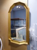 A GILT FRAME ARCH TOPPED WALL MIRROR, WITH SMALL SHELF BELOW WITH MIRROR GLASS TOP